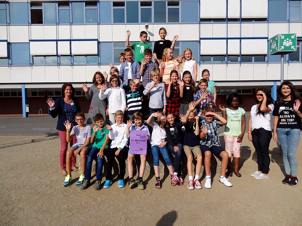Klassenfoto einer neuen fünften Klasse mit erhobenen Armen.